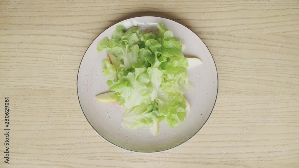 Male hands put lettuce on plate on wooden table, top view Male hands put lettuce on plate on wooden table, top view