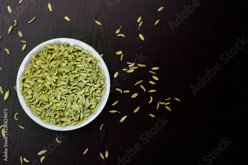 fennel seeds in ceremic bowl on dark wooden background , top view