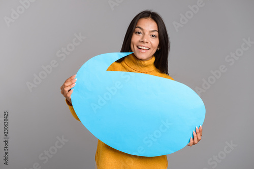 Quadro su tela Happy woman posing isolated over grey wall background holding speech bubble