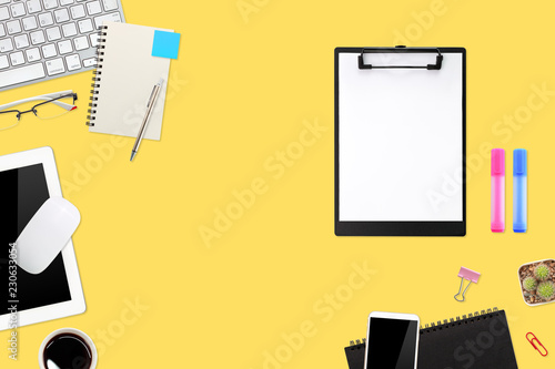 flat lay workspace table with laptop computer, office supplies, coffee cup, tablet and cell phone on yellow pastel background