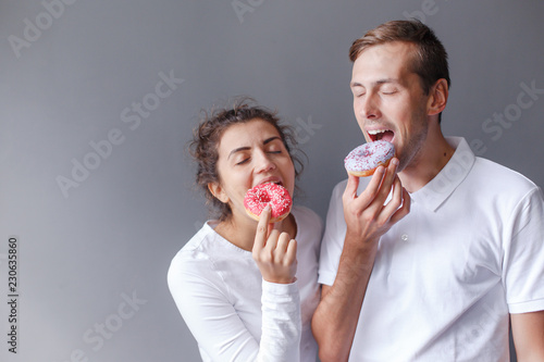 Portrait a guy with a girl who are fooling around with donuts