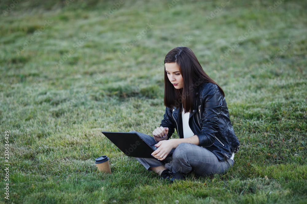 Young business woman sitting and working in park with laptop Young business woman sitting and working in park with laptop