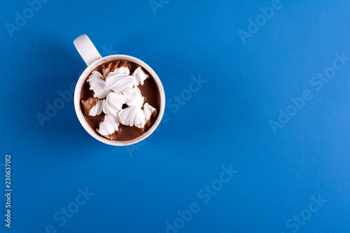 Hot chocolate with marshmallow candies on blue paper background. Top view. Copy space. Toned