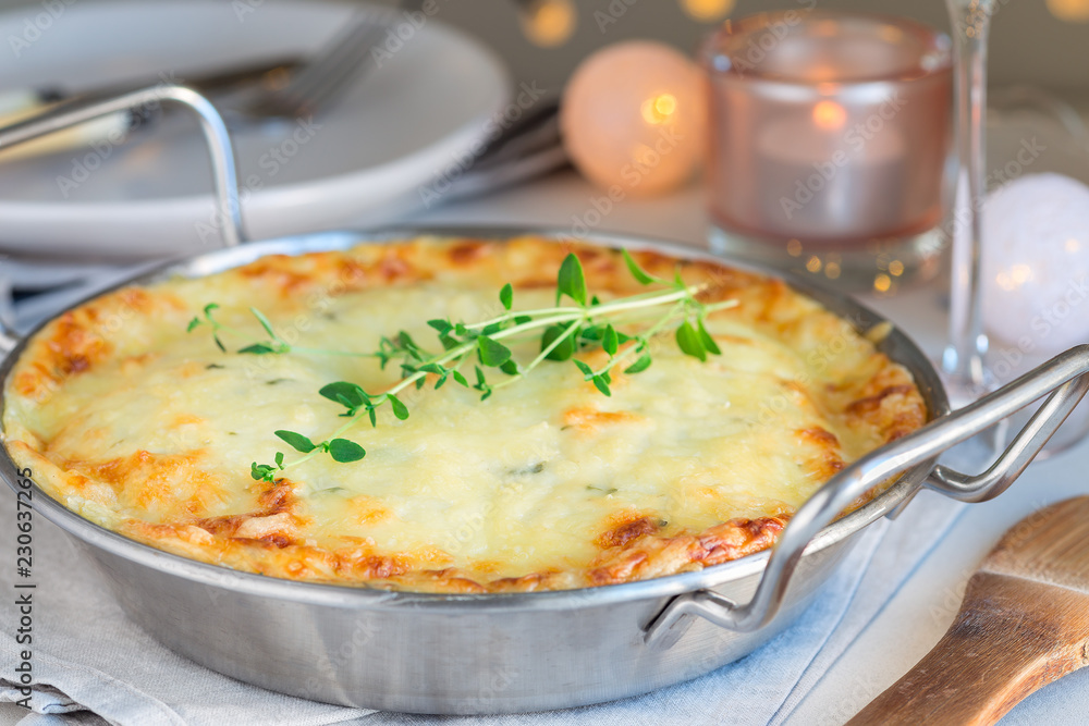 Cheesy scalloped potatoes or potato gratin in a baking dish, holiday theme, horizontal Cheesy scalloped potatoes or potato gratin in a baking dish, holiday theme, horizontal