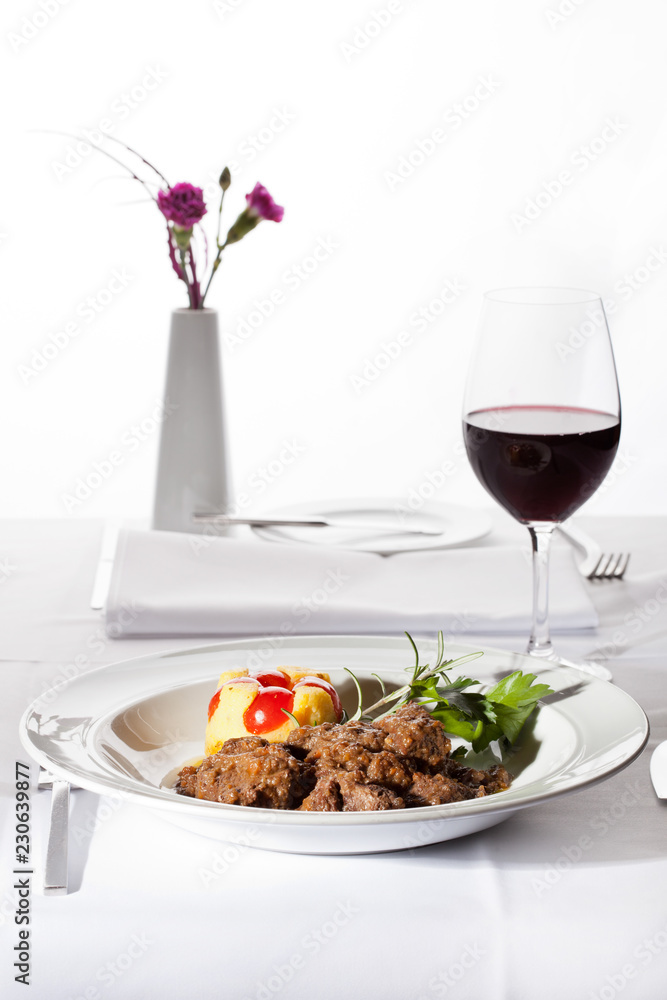 Goulash and red wine served in restaurant on white