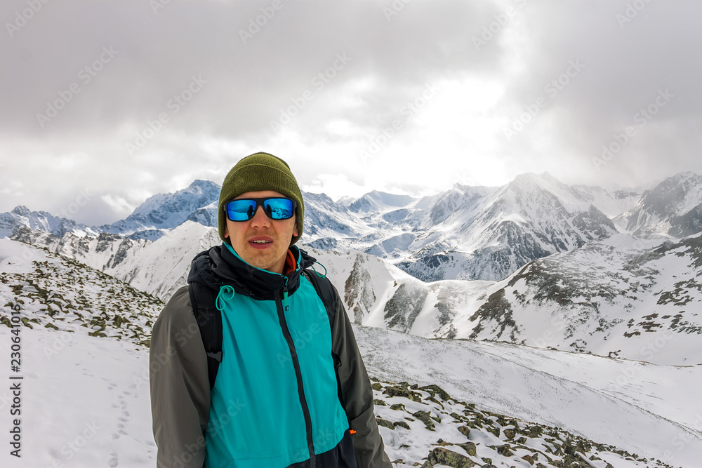 portrait male mountaineer in snowy mountains, with a backpack