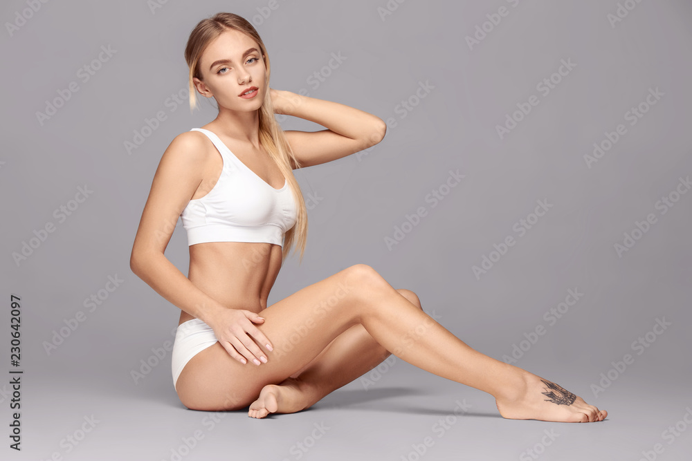 Perfect slim toned young body of the girl or fit woman at studio. The fitness, diet, sports, plastic surgery and aesthetic cosmetology concept.