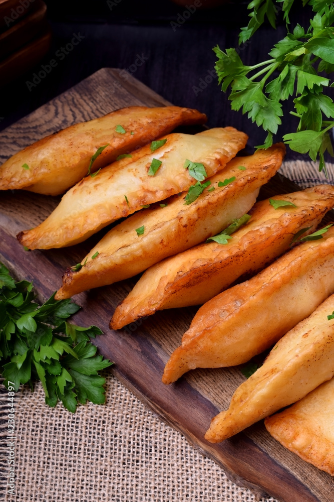 Fried chebureks with meat on a wooden board Fried chebureks with meat on a wooden board