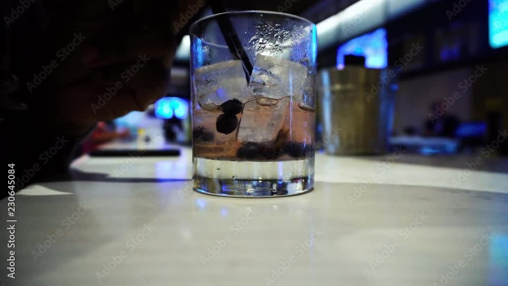 close up view of main drinking a mixed alcoholic cocktail at a local bar by himself during the summer close up view of main drinking a mixed alcoholic cocktail at a local bar by himself during the summer