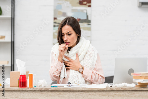 sick young businesswoman having cough at workplace