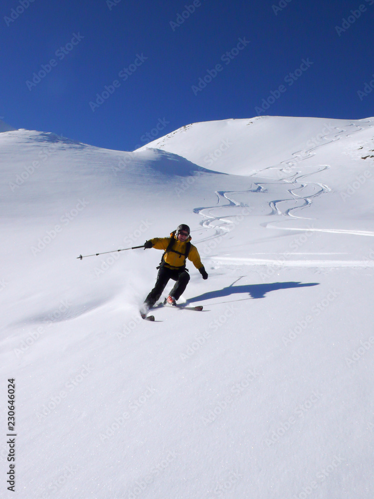 female backcountry skier enjoys a great powder snow descent in deep winter in the Swiss Alps