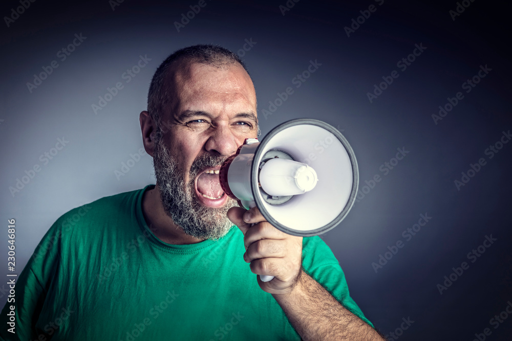 Caucasian man with beard yells into a megaphone to make himself heard. concept of desire to emerge and difficulties in personal communications. Caucasian man with beard yells into a megaphone to make himself heard. concept of desire to emerge and difficulties in personal communications.