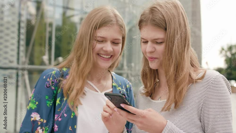 Attractive young ladies using a phone in town. Medium dolly shot Attractive young ladies using a phone in town. Medium dolly shot