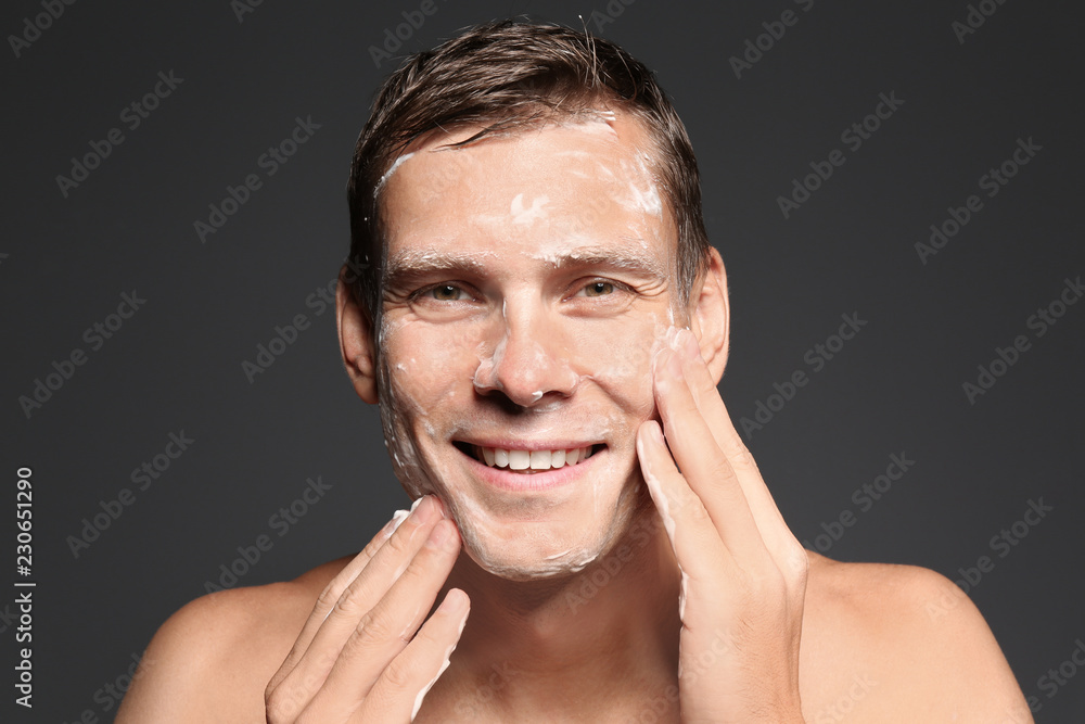 Obraz premium Man washing face with soap on dark background
