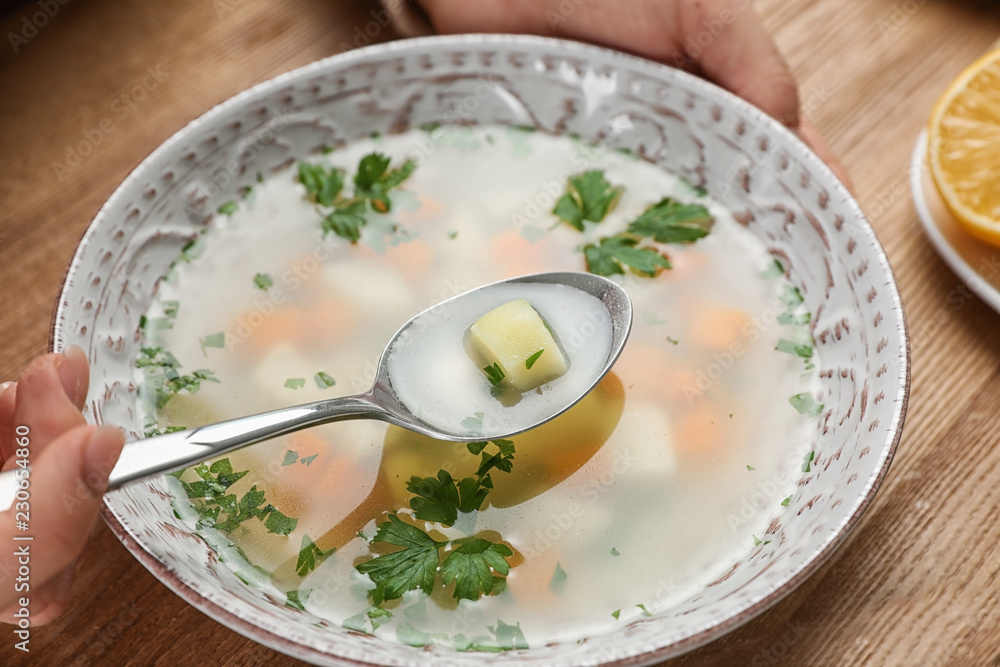 Sick woman eating fresh homemade soup to cure flu at table, closeup Sick woman eating fresh homemade soup to cure flu at table, closeup
