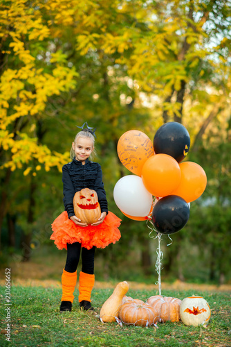 Girl holding pumpkin at Halloween party with orange and black balloons
