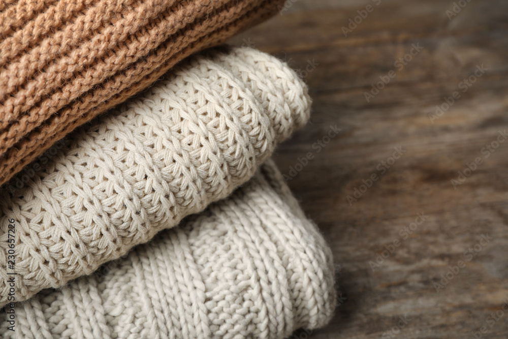 Stack of folded knitted sweaters on table, closeup. Space for text Stack of folded knitted sweaters on table, closeup. Space for text