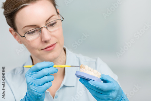 Zahntechnikerin färbt einen Zahnersatz im Zahnlabor