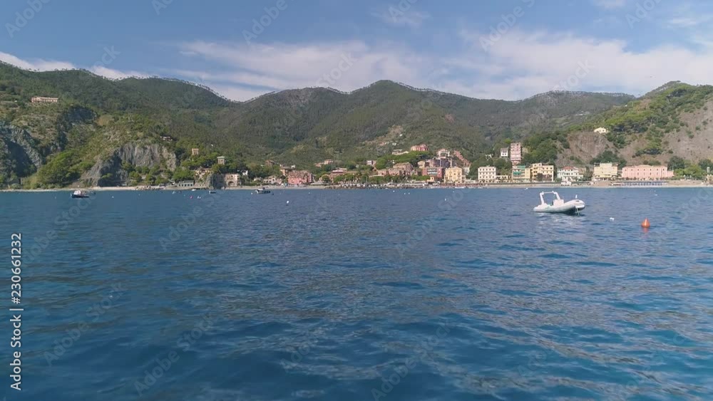 Aerial: Slow motion Beautiful town village on the coast of Mediterranean sea Large mountains behind Passing by motor boat Sunny day Italy Aerial: Slow motion Beautiful town village on the coast of Mediterranean sea Large mountains behind Passing by motor boat Sunny day Italy