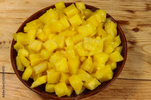 Diced pineapple in a plate on wooden table. Top view
