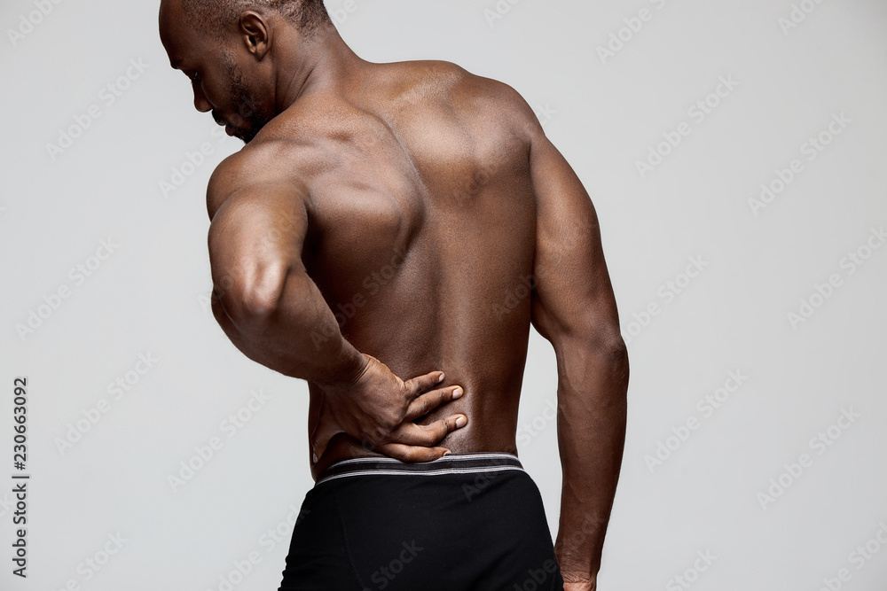 Young man with back pain isolated on gray studio Young man with back pain isolated on gray studio