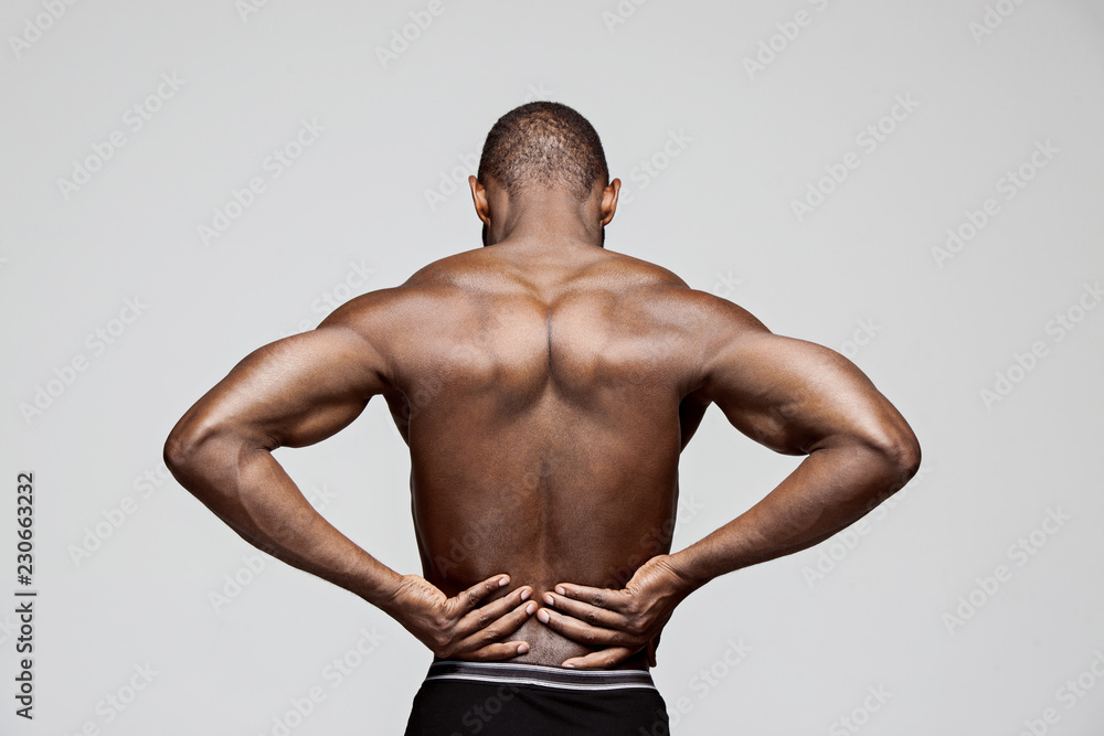 Young man with back pain isolated on gray studio