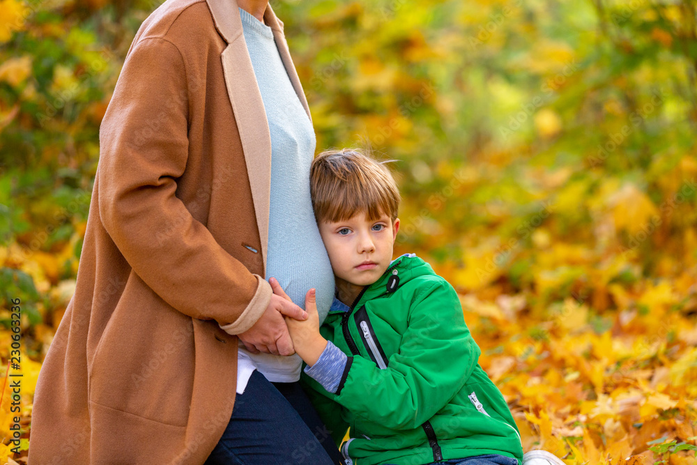 Cute sweet Caucasian child listening to his pregnant mother's belly