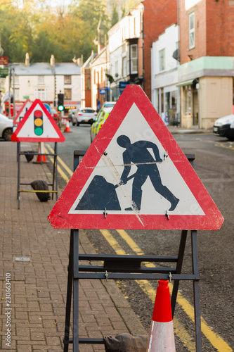 Temporary road works signs and traffic lights controlling vehicle access during highway repairs on a typical British urban street photo