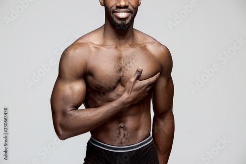 Young african american man with white shirt having a pain in the heart. Heart attack isolated on gray background