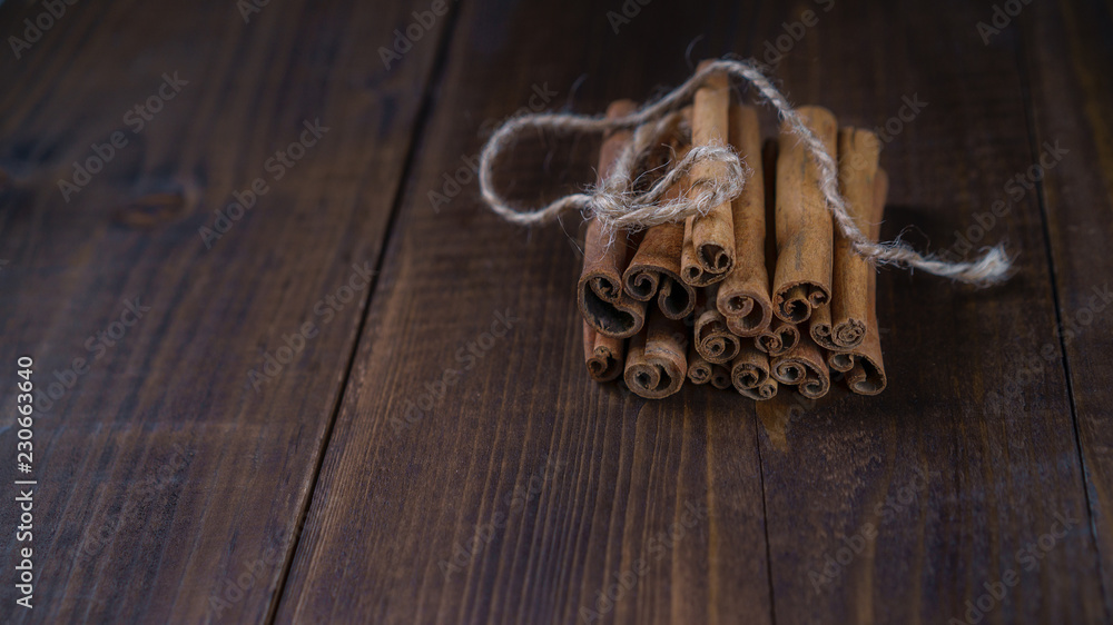 Cinnamon sticks tied with jute rope on old wooden background in rustic style. Winter Christmass holiday concept. Close up. Cinnamon sticks tied with jute rope on old wooden background in rustic style. Winter Christmass holiday concept. Close up.