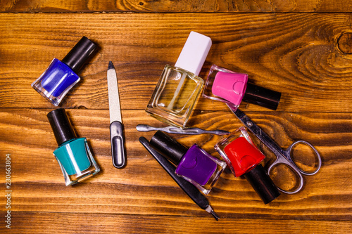 Different manicure tools and nail polishes on wooden table. Top view