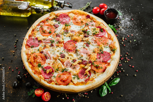Pizza with salami and ham on black background