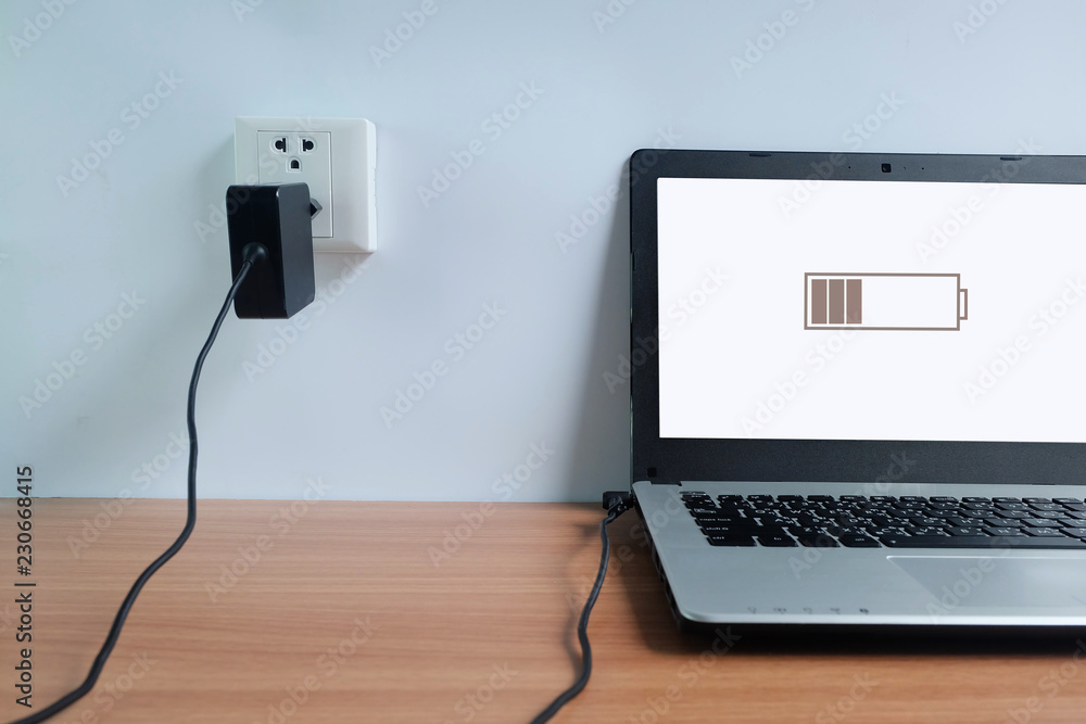 Plug in power outlet adapter cord charger on a white wall of the laptop  computer on Wooden floor Stock Photo | Adobe Stock