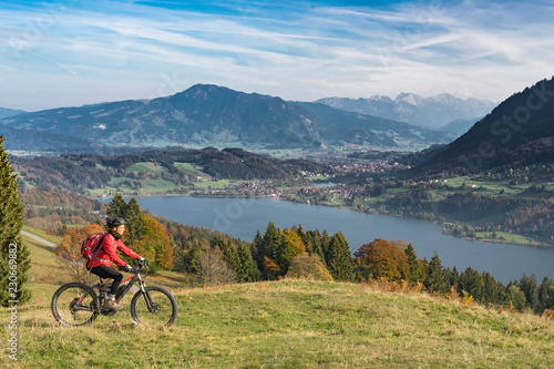 nice senior woman  riding her E-mountainbike in the indian summer on the mountains above the Alpsee near Immenstadt  Allgaeu  Bavaria  Germany