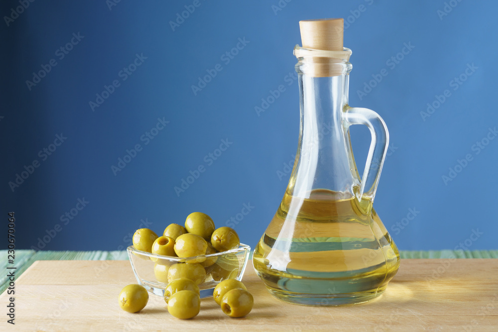 Bottle with oil and and olives on a wooden board, on a blue background Bottle with oil and and olives on a wooden board, on a blue background
