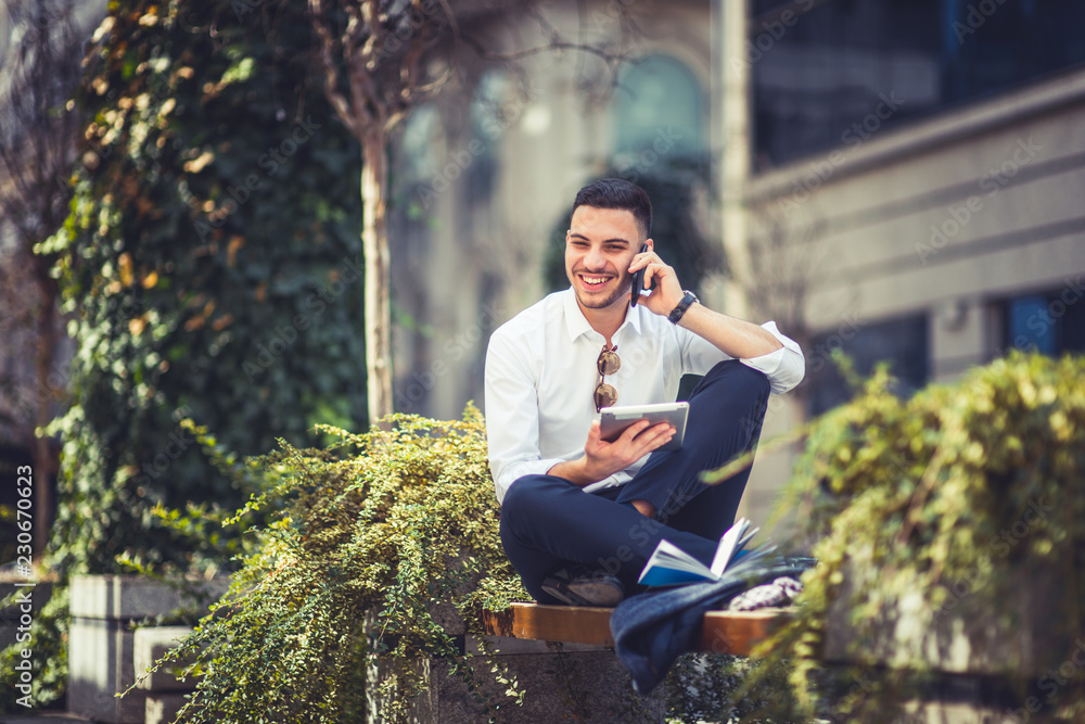 Urban businessman sitting on the bench, looking at his tablet Urban businessman sitting on the bench, looking at his tablet
