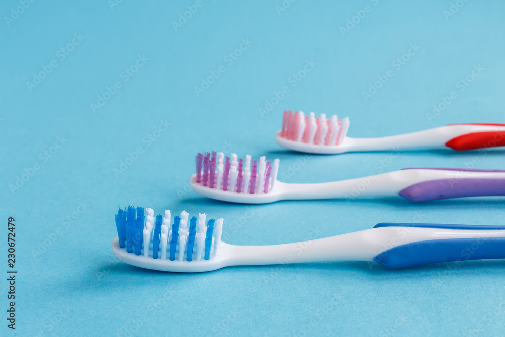 concept of dental health. Three multicolored toothbrush and toothpaste on a blue background. Design, health care, healthy hygiene concept of dental health. Three multicolored toothbrush and toothpaste on a blue background. Design, health care, healthy hygiene