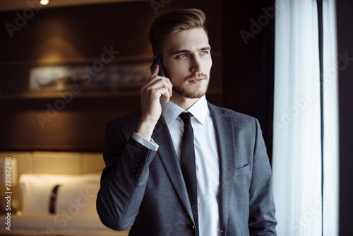 Young handsome man relaxing at his apartment in a hotel after business meeting. Business trip. Booking hotel during your vacation. Businessman in luxury room of the expensive beautiful hotel. 