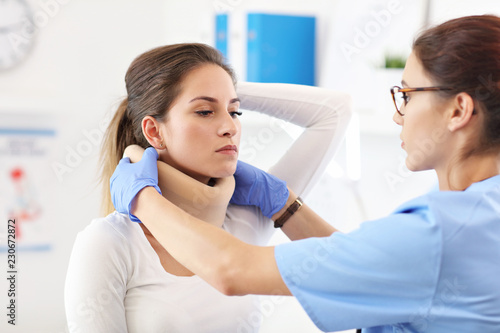 Female doctor putting neck orthopaedic collar on adult injured woman