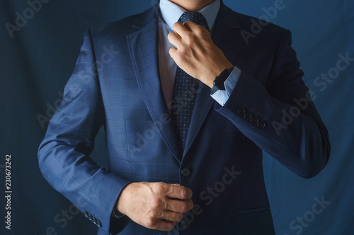 A man in a blue suit straightens his tie