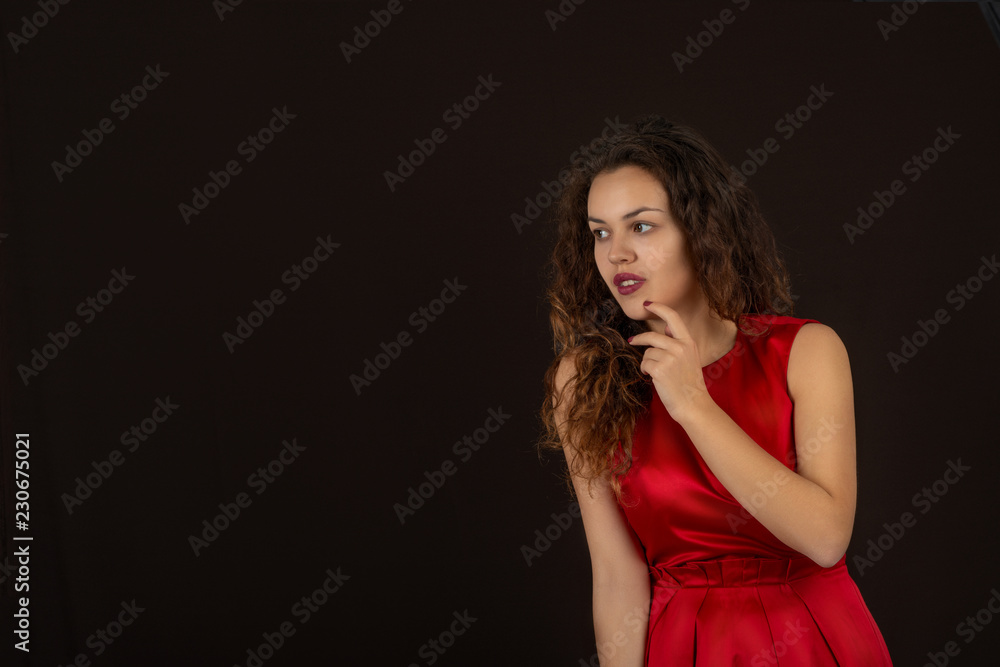Waist up portrait of a young woman wearing black red dress with long curly hair on a dark burgundy background with copy space in the studio Waist up portrait of a young woman wearing black red dress with long curly hair on a dark burgundy background with copy space in the studio