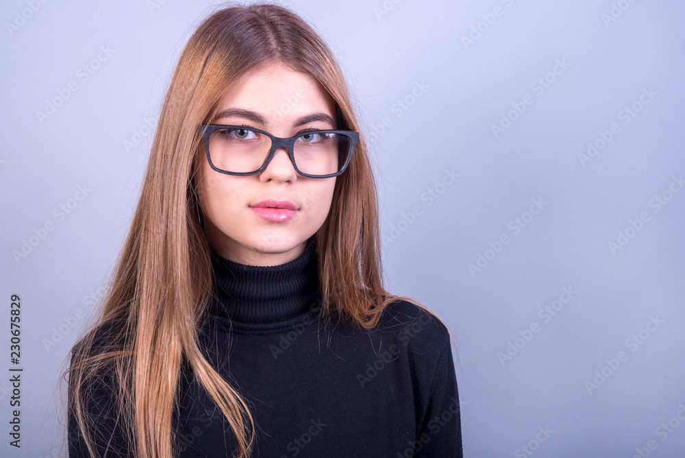 Young beautiful girl with glasses standing in front of grey background Young beautiful girl with glasses standing in front of grey background