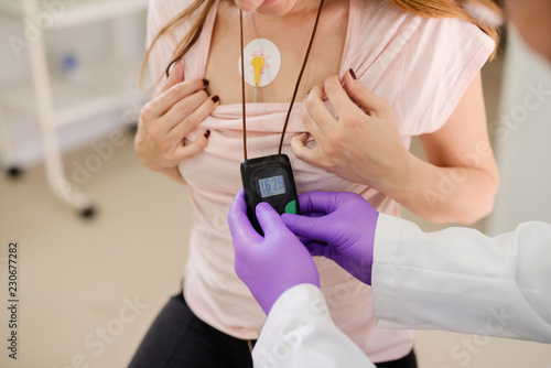 Close up of doctor putting holter on woman`s chests. photo