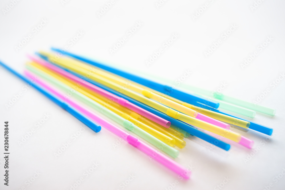 Multiple plastic straws laying on a white background