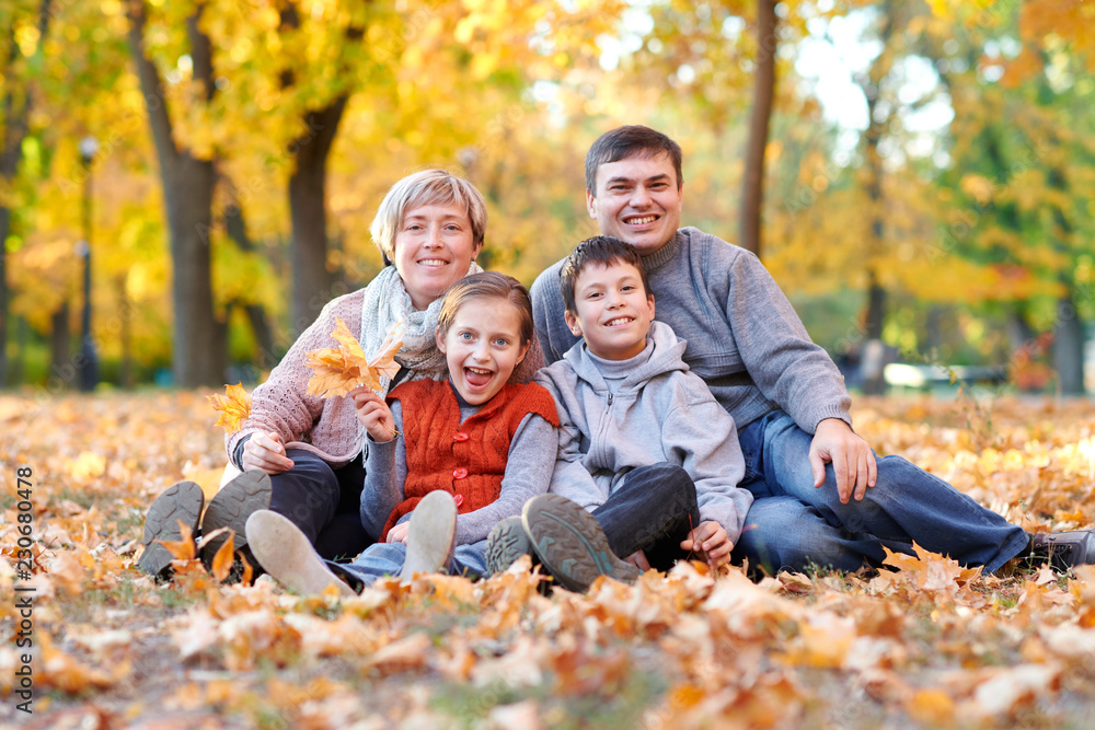Happy family lies in autumn city park on fallen leaves. Children and parents posing, smiling, playing and having fun. Bright yellow trees. Happy family lies in autumn city park on fallen leaves. Children and parents posing, smiling, playing and having fun. Bright yellow trees.