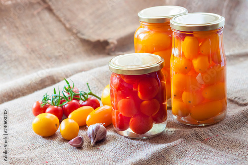 Fotografia Glass jars with homemade pickled tomatoes, sealed with metal lid