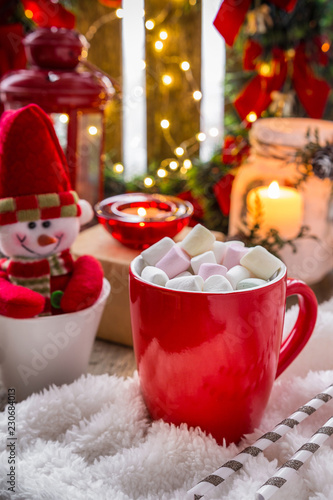 Christmas holiday arrangement.  Cup with hot cocoa marshmallows with candles, gifts, a cozy fluffy blanket.  concept of peace and comfort at home in Christmas. New Year winter background greeting card