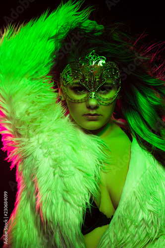 Close up portrait of curvy alternative model with colored hair and fur coat and fishnets under green and pink lighting