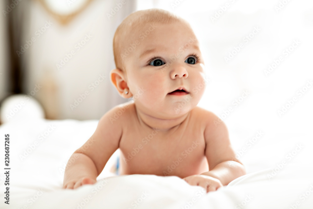 A Cute baby girl on a white bed at home