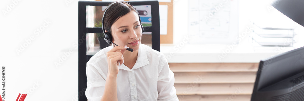 A young girl in headphones with a microphone sitting at a computer table. A young girl in headphones with a microphone sitting at a computer table.